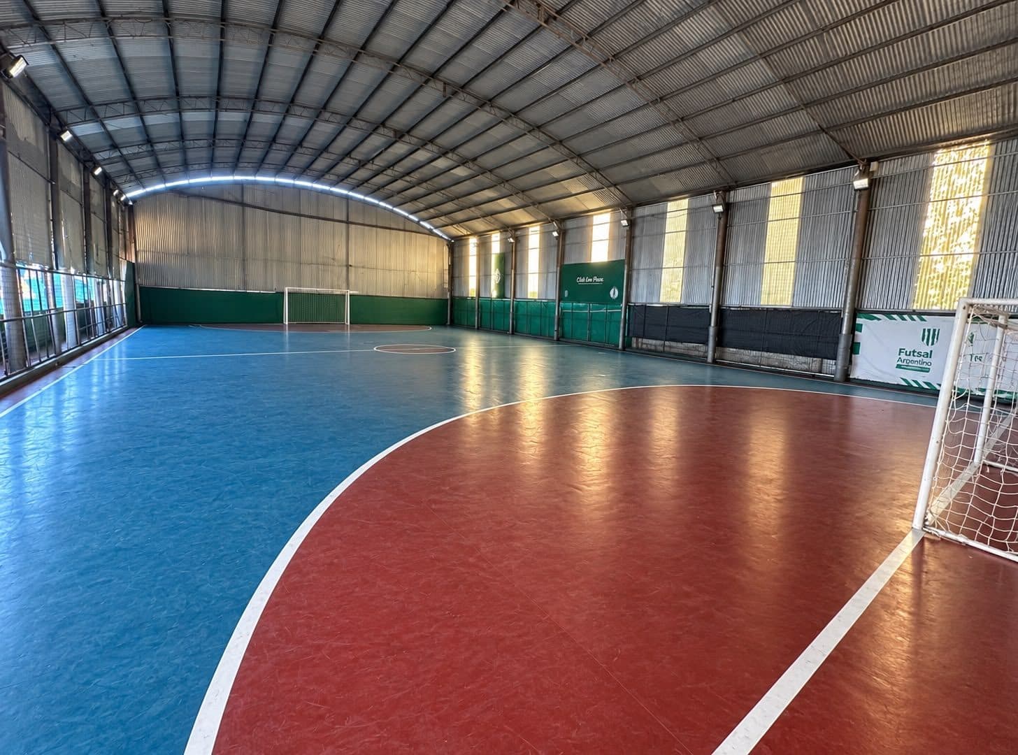 La cancha de fútbol techada del club, con los arcos puestos y el piso pintado.